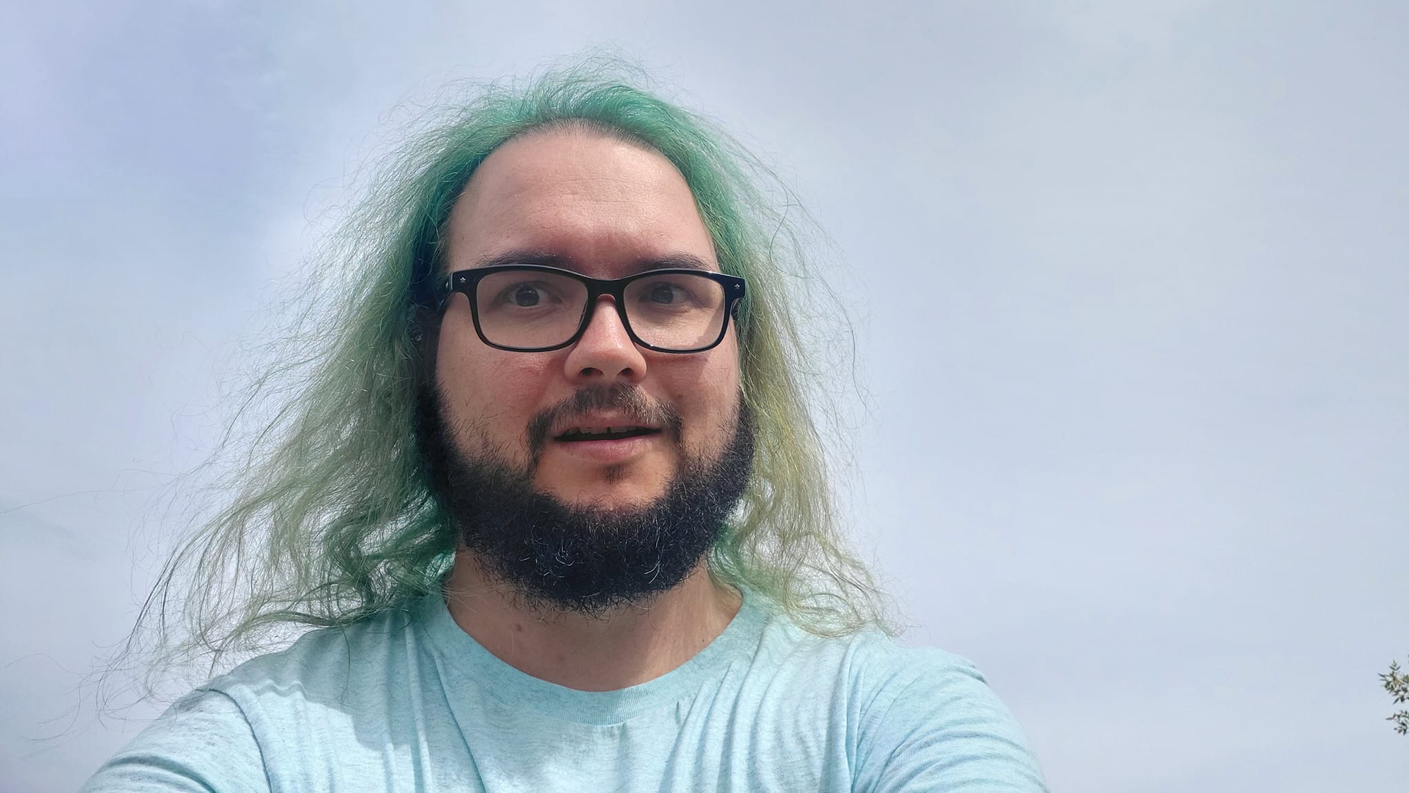 A man with green hair stands with only the sky visible in the background, Photo 1